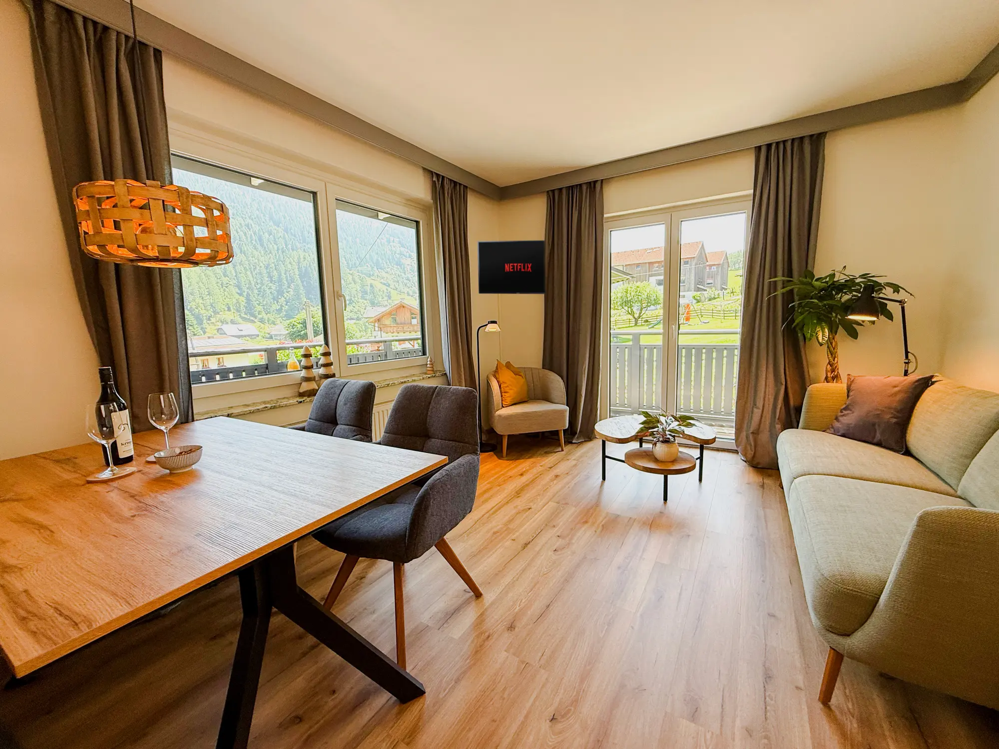 Wohnzimmer der Ferienwohnung Fuchs mit Panoramafenstern, Esstisch und Sitzecke